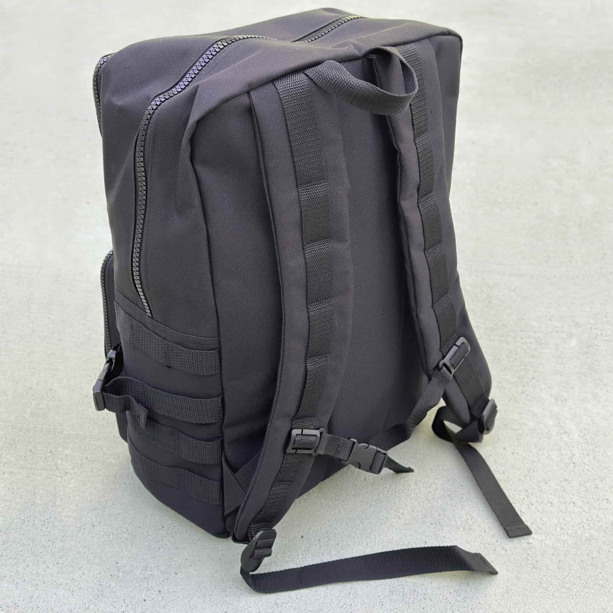 The Tactical Bag in black with hook and loop areas and MOLLE system on the back, seen from the carrying side